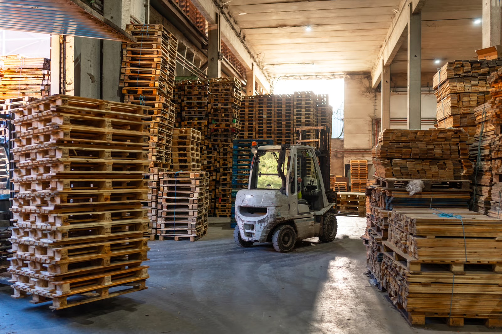Illustrative warehouse scene: a forklift beside stacks of Euro-format timber pallets.